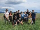 teens and adults posing for a group photo in a grassy field