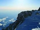 view from high atop a snowy mountain, looking down at plumes of smoke