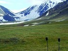 two microphones in a tree-less meadow near steep, snowy mountains