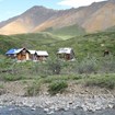 rustic buildings near a creek, hills and mountains in the distance