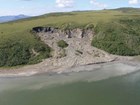 treeless hillside partially collapsed into a river at its base