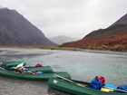 three large canoes in a shallow river