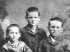 An eight year old boy poses for a portrait in 1881 with his younger sister and older brother.