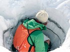a person samples layers of ash in a snow hole