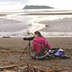 A researcher looking through a scope on the beach.