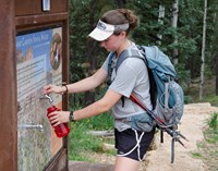 Hiker filling her water bottle at a drinking water station in the Grand Canyon.
