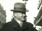 A 1919 photo depicts a man in a hat and coat touring a European city street.