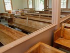 An open partition separates wooden benches in a plainly furnished house of worship.