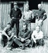 Black and white photo of six white men standing in front of an old National Park Service Building. 