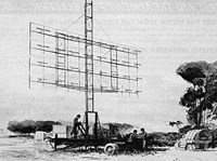 A tower of radar equipment sits on a towed trailer with three men standing on it