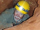 person with helmet in narrow cave passage
