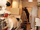 A sergeant works on a diesel tank inside a generator room
