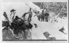 Men struggle up a snow covered canyon with their sled.
