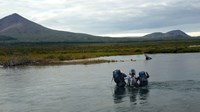 3 backpackers cross a river