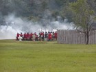 Reenactors representing British regular soldiers firing a volley from black power muskets.