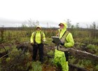 Two fire ecologists in bright, lime-yellow rain suits, monitor the impacts of multiple fires.