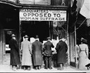 Men standing with their backs to camera under sign opposing women's suffrage. Library of Congress. 