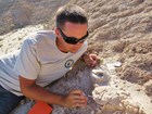 paleontologist pointing to an exposed fossil 
