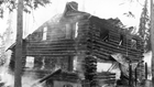 a two-story log cabin on fire in a snowy forest