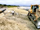 heavy equipment spreading sand on a beach