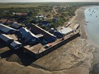 Aerial view of cannery on a wide shore, with large warehouse buildings and smaller structures