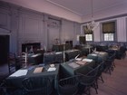 Color photo of a room with rows of desks facing one main table in the front of the room.