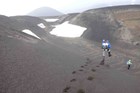 A man jumps down a dune of volcanic ash.