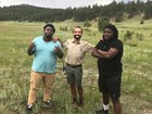 three men standing in a grassy field