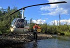 A helicopter landed on a small stream bank.