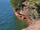A view of the cliff with caves carved at the water. 
