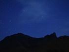 Bright stars and wisps of galactic dust glow in a deep blue night sky.