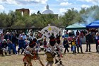 four dancers, painted white, with black face-coverings, dance in front of a crowd