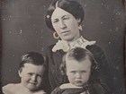Black and white photo of a woman, Julia Grant, posed with two young children. 