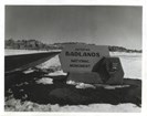 a historic black and white photograph shows the park sign reading entering badlands national park