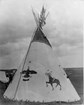 a black and white photograph shows a tipi decorated with hand painted images of animals.