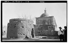 black and white photo of round mortuary chapel and back of church with dome, man in foreground
