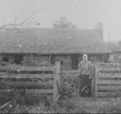 An older woman standing in front of a house