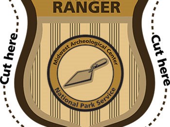 Gold badge that says JUNIOR RANGER Midwest Archeological Center with a trowel in the center