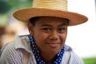 A boy wearing a straw hat and a striped shirt.
