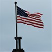 An american flag flying from a wooden flagpole. 