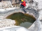 A scientist writing notes by a pool of water in a bedrock depression.
