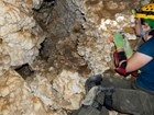 a person in a cave with hard hat and headlamp