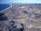 Vast, blackened landscape with beaches and bluffs beyond.