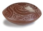 A red, convex-shaped pottery with a white, swirling design.