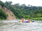 Floaters on tubes on a river with a tan bluff and blue sky behind.
