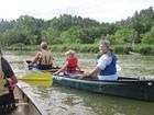 Three people in a canoe, one turned back smiling at the camera.