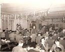 Black and white photo of men in decorated mess hall. 