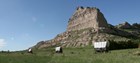 Three covered wagons are seen in front of a distinctive rock formation.
