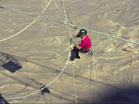 An Engineer suspended above the Colorado River works on construction of the Trans-canyon Waterline