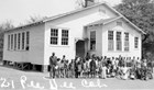 Photo of students in front of schoolhouse. 